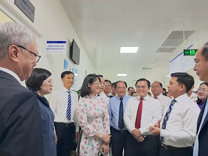 BS-CKII Trần Văn Sóng, Giám đốc Bệnh viện Nhân dân 115 (thứ 2 từ phải vào) giới thiệu về phòng khám vệ tinh của bệnh viện cho các đại biểu. Ảnh: QUANG HUY 5.jpg