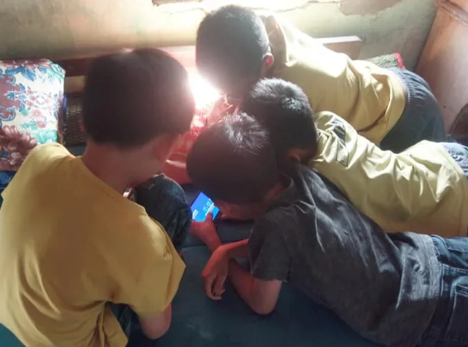 Nhóm trẻ chụm đầu chơi game trên điện thoại trong kỳ nghỉ hè (ẢNH: SƠN VINH)