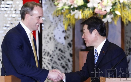 日本外相茂木敏充（右）與英國外交大臣拉布握手。（圖源：共同社）