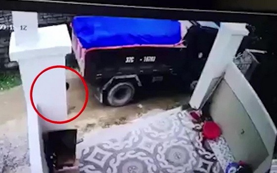 監控視頻顯示，站在車後的一名男童（紅圈示）不幸遭卡車倒車時輾壓當場死亡。（圖源：視頻截圖）