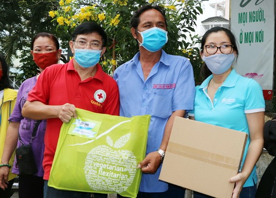 第五郡紅十字會主席黎勛峰（左）與「Habitat」項目管理人胡氏梅英（右）向貧困戶贈送禮物。