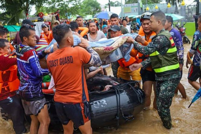 救援人員協助居民從洪災區轉移。（圖：新華社）