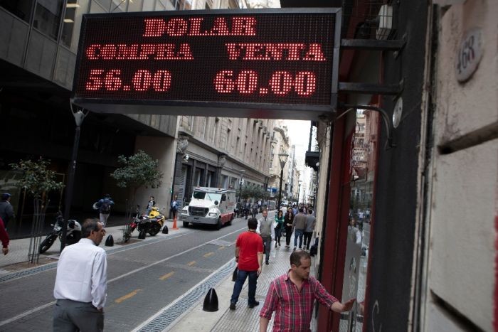圖為 2019年8月28日，在阿根廷首都布宜諾斯艾利斯，行人走過外幣兌換點。（圖：新華社）