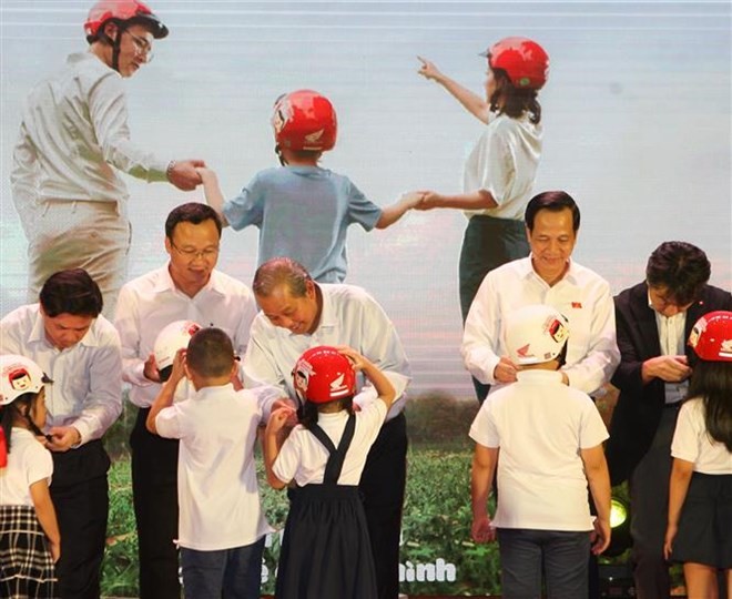 Deputy Prime Minister Truong Hoa Binh (third from left) presents a helmet to a first grader on June 12 (Photo: VNA)