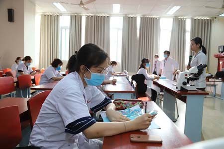 Students of HCMC University of Medicine and Pharmacy strictly observe protection rules when coming to school. (Photo: SGGP)