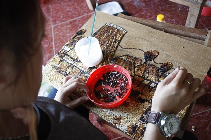 Participation: A tourist learns to make a rice painting under the guidance of Dang. (Photo: VNS)