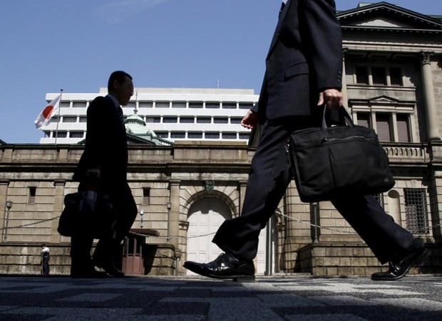 Japanese office workers walk on a street in front of the Bank of Japan headquarters in Tokyo. (Photo: Reuters)