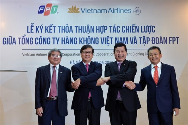 Representatives of Vietnam Airlines and FPT Corporation shake hands after signing strategic co-operation agreement in Hanoi. (Photo: VNA)