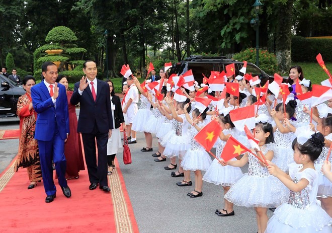Indonesian President Joko Widodo (L) is welcomed by Vietnamese children at the official welcome ceremony for him and his spouse in Hanoi on September 11 (Photo: VNA)
