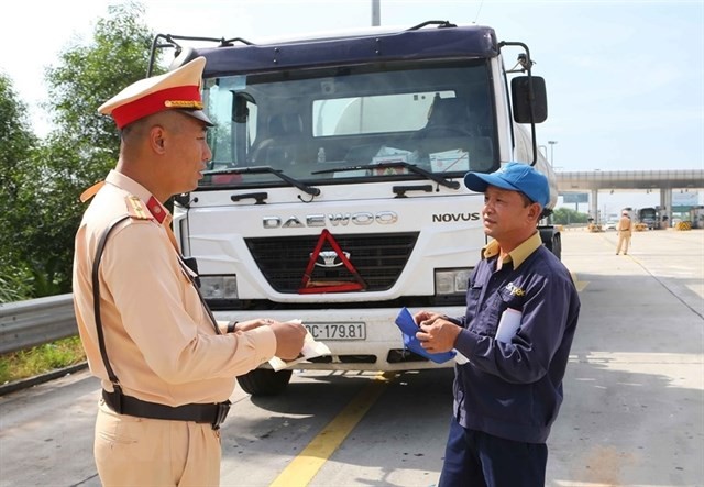 A member of the traffic police checks the paperwork of a truck driver on the Hanoi-Hai Phong Expressway. (Photo: VNA)