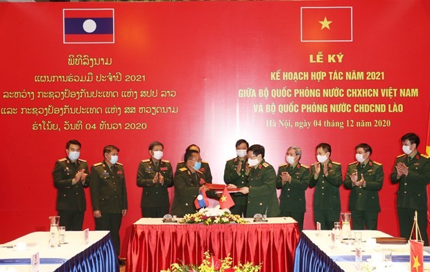 The defence ministers of Vietnam and Laos exchange the signed 2021 cooperation plan in Hanoi on December 4 (Photo: VNA)