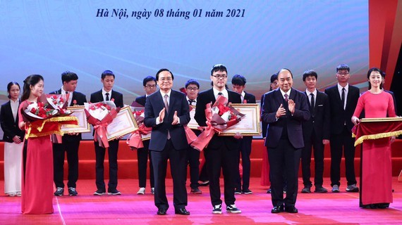 Prime Minister Nguyen Xuan Phuc (R) and Minister of Education and Training Phung Xuan Nha present certificates of merit to students. (Photo: SGGP)